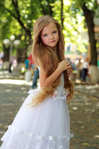 在美丽的白色礼服，户外散步的长期健康头发的迷人年轻女孩