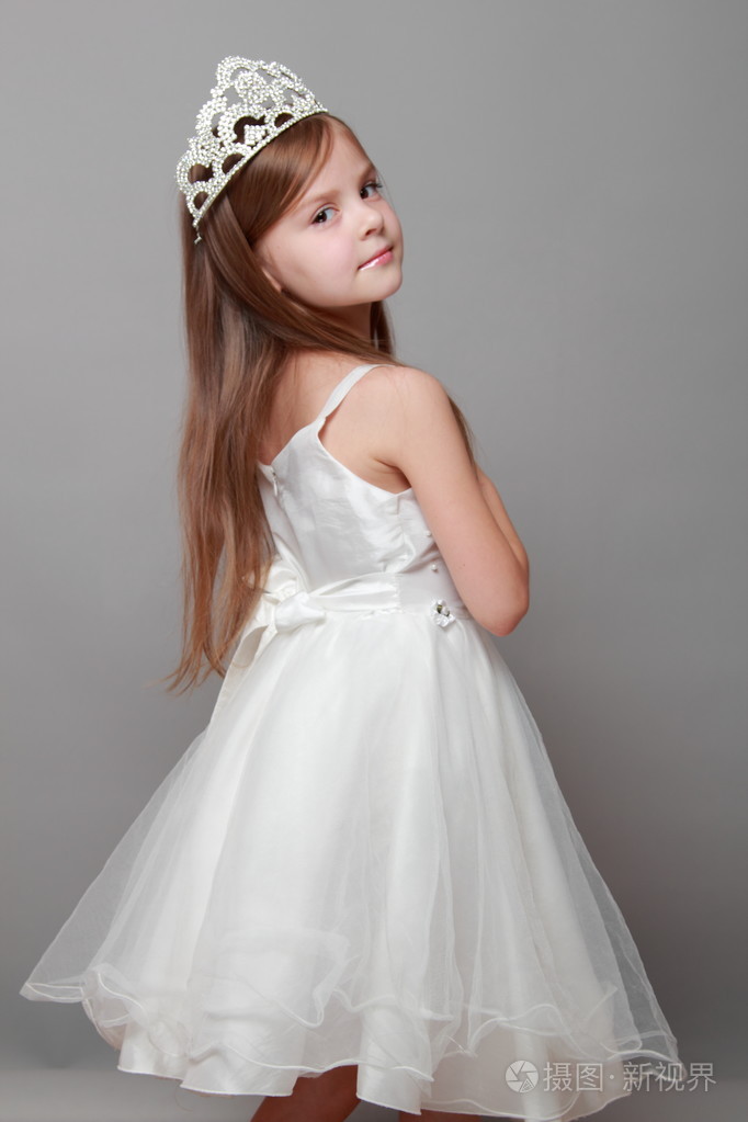 漂亮的小女孩在灰色的背景上的长头发穿公主裙