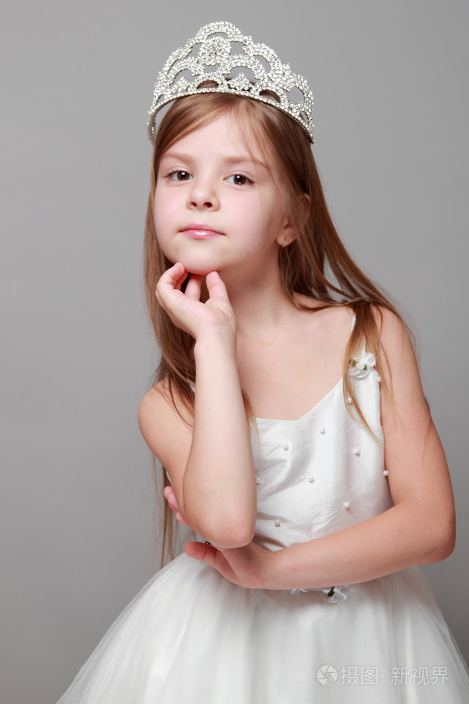 皇冠和可爱的笑容摆在灰色的背景上的摄像头白色连衣