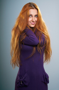 有魅力的年轻女人在淡紫色礼服。红色的长头发