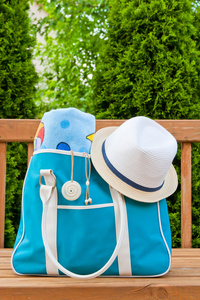 蓝色袋用毛巾和室外游泳池或海滩周末的帽子