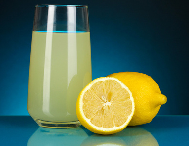 在玻璃和它旁边暗蓝色背景上的柠檬美味柠檬汁