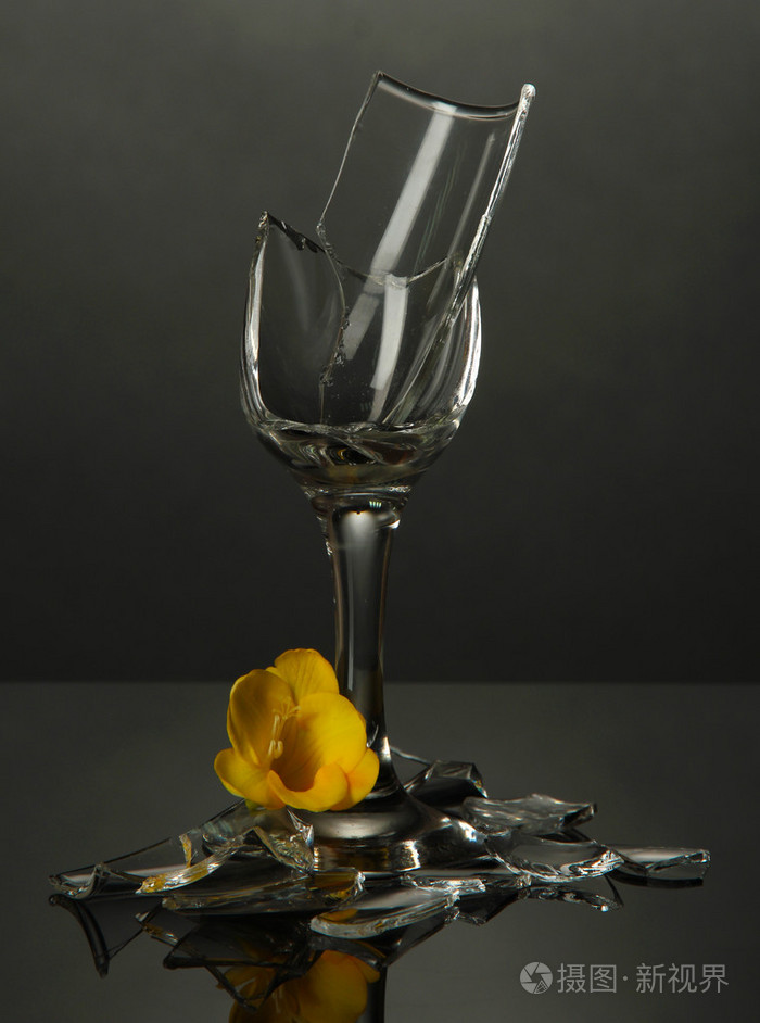 碎的酒杯与灰色的背景上的花