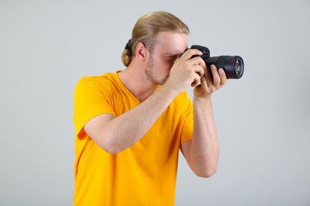 帅气摄影师用相机上的灰色背景