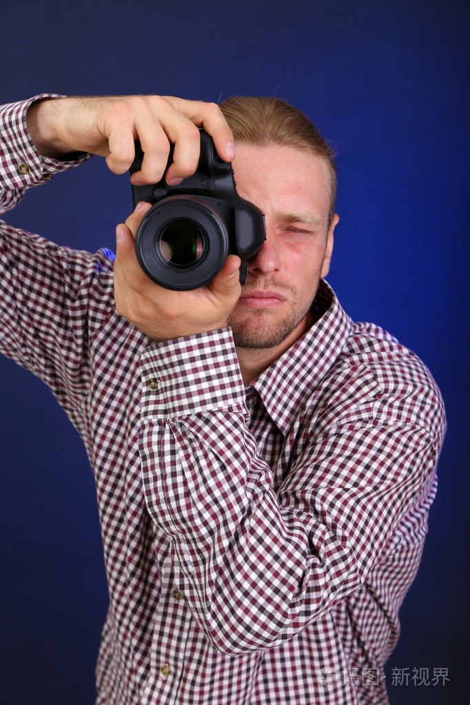 帅气摄影师用相机,深色背景上