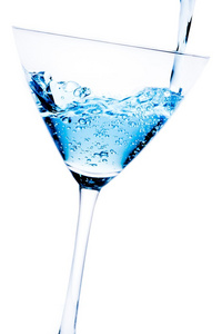 用蓝色鸡尾酒倾斜和泡沫填充玻璃