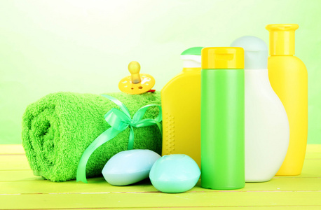 婴儿化妆品 肥皂和毛巾木桌上，在绿色背景上