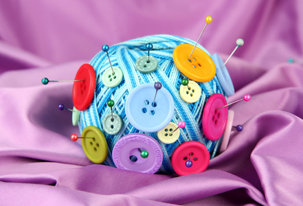 多彩按钮和羊毛球，彩色织物背景上