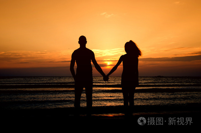 情侣在海滩上享受他们在日出的时间