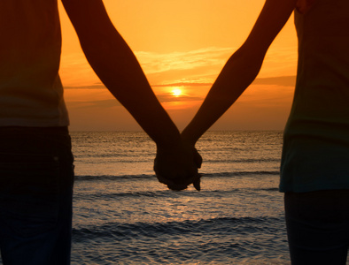 情侣在海滩上享受他们在日出的时间照片