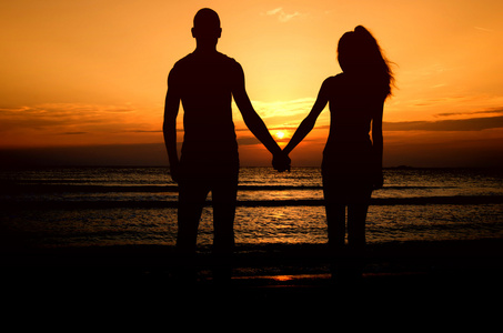 情侣在海滩上享受他们在日出的时间