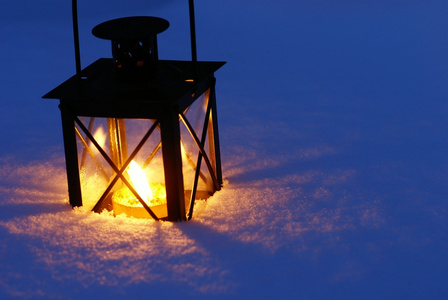 在雪上的蜡烛烧在晚上与灯笼