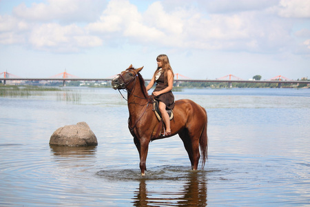 美丽少女骑着马在河中