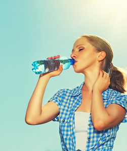 女人喝水从瓶子在夏天户外在 s