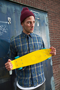 都市时尚滑板手与持有他 skateboar 的羊毛帽子