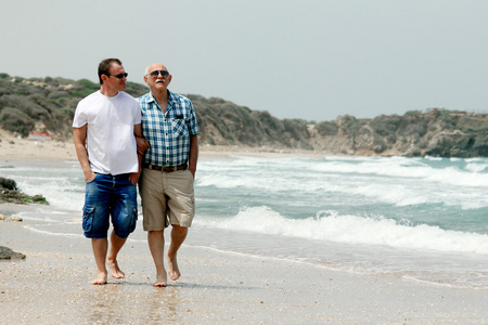 成人的儿子和父亲一起在沙滩上散步