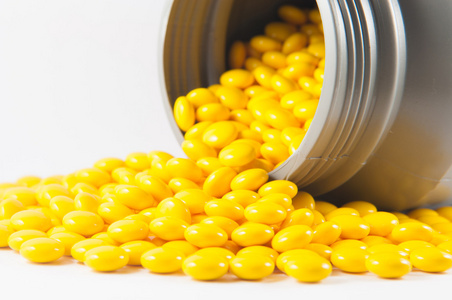 黄色糖衣的片和白灰色塑料瓶照片