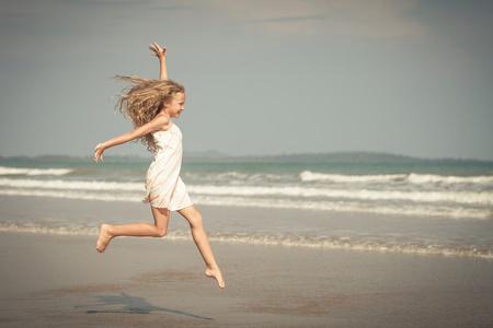 飞行在暑假期间在蓝色的大海岸上跳沙滩女孩
