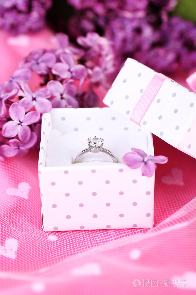 美丽的盒子与紫色背景上的结婚戒指