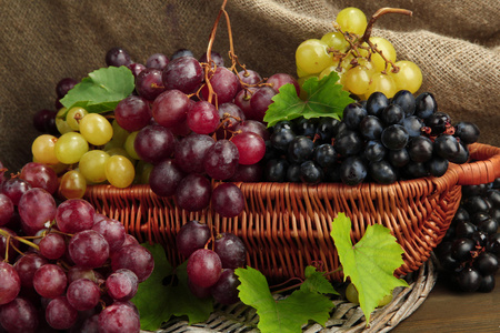 熟透的甜葡萄在篮子里，麻布背景上的分类