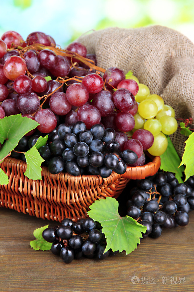 熟透的甜葡萄在篮子里在绿色背景上的分类