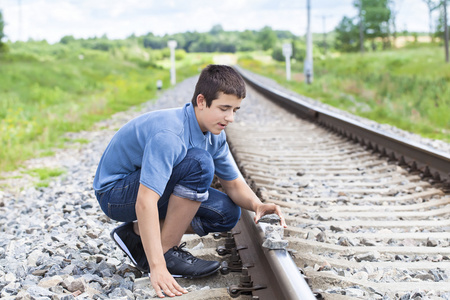 男孩把石头放在铁路轨道上