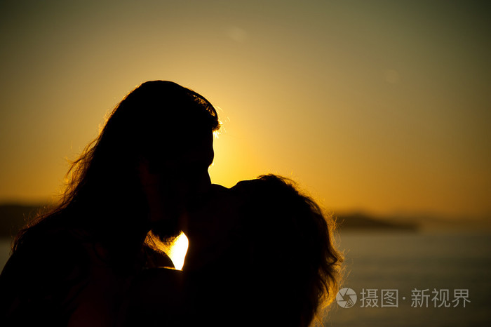 爱情侣接吻在夕阳下的海滩