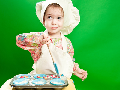 做饭的厨师的帽子和一条围裙的小女孩