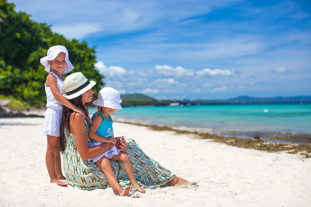 年轻的母亲和两个孩子在异国海滩上阳光灿烂的日子