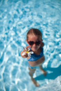 小可爱的快乐女孩显示花的游泳池