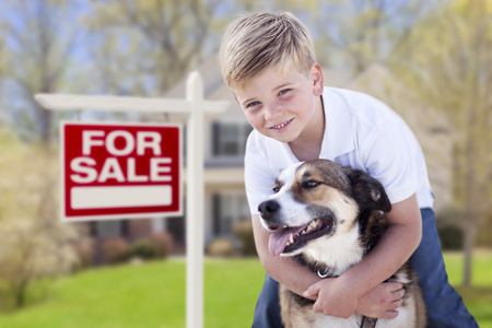 小男孩和他的狗的前面出售标志和房子