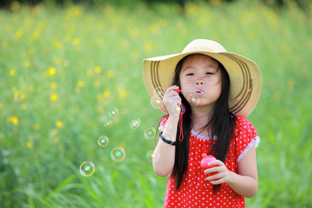 快乐的女孩黄色花场玩肥皂泡