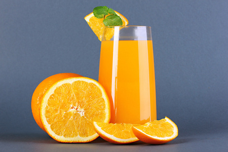 杯橙汁与薄荷和灰色的背景上的橙色