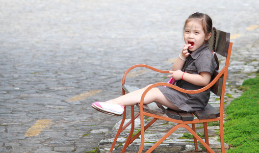 可爱微笑着坐在长凳上的小女孩