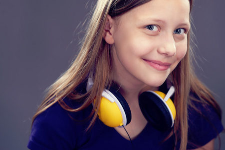 微笑着的十几岁的女孩用耳机的肖像