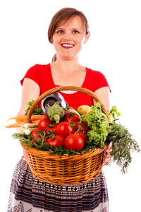 快乐的年轻女子，显示一个大篮子新鲜蔬菜
