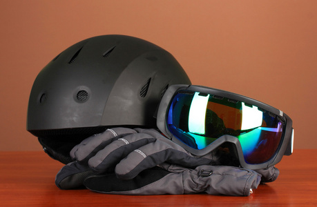 冬季运动眼镜 头盔 手套 棕色背景上