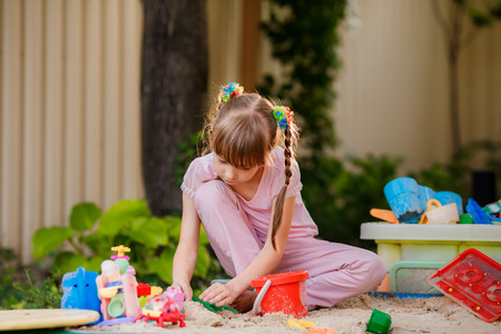 在沙盒中玩玩玩具在沙盒中的可爱小女孩照片