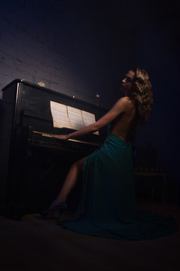 弹钢琴的晚装裙的美丽女人