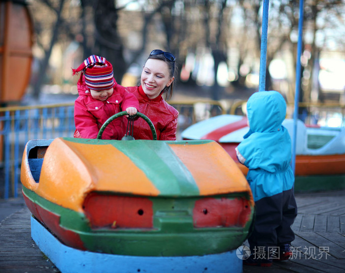 母亲和两个小女孩骑着旋转木马车