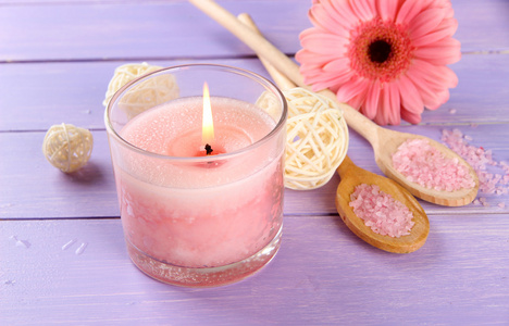 美丽粉红色蜡烛带紫色木制背景上的花