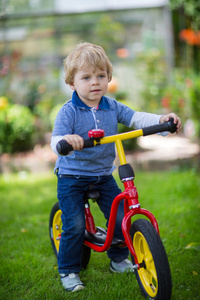 2 岁小孩骑在他的第一辆自行车上