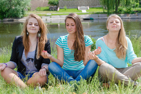 三个少女坐在瑜伽的立场和打坐