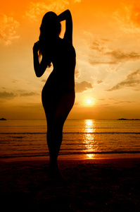 日出时在海滩上的女人的剪影