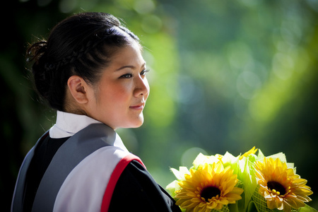 年轻的毕业女人与黄色的花朵