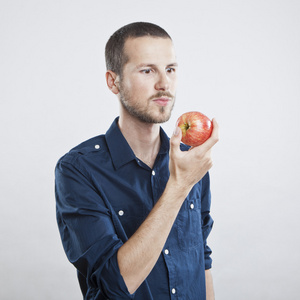 性格开朗美丽的男人吃苹果，孤立在白色背景