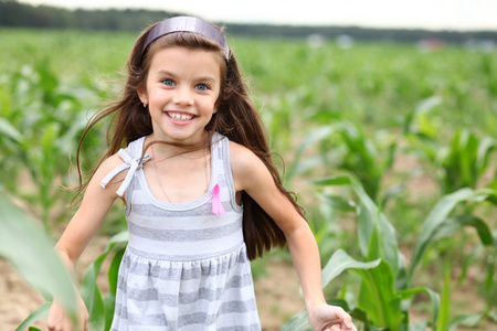 快乐的小女孩通过玉米字段运行