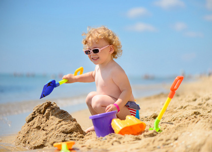 可爱的小女孩在玩沙的太阳镜