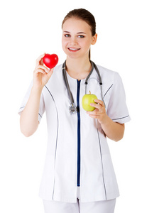 微笑的女人医生与绿色苹果和红色的心