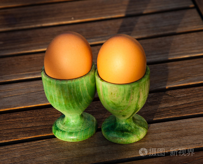 两个鸡蛋在绿色木蛋杯